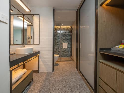 a bathroom with a sink and a toilet and a mirror at Sanya Haitang Bay Moutai Resort Boutique Hotel in Sanya