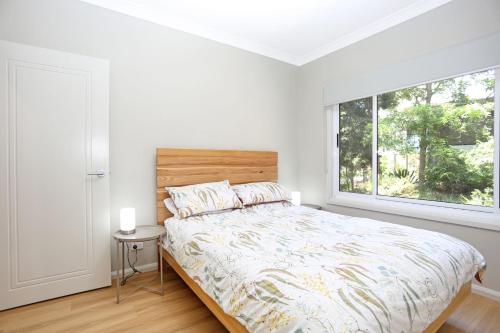 a white bedroom with a bed and a window at Wylah in North Arms Cove