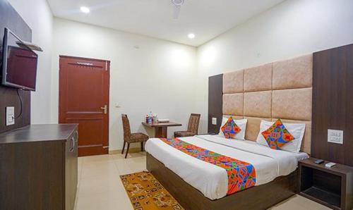Schlafzimmer mit einem Bett, einem Tisch und einem TV in der Unterkunft FabHotel Grand Model Town Inn in Jalandhar