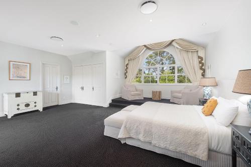 een witte slaapkamer met een groot bed en een raam bij Iona Park, Moss Vale in Moss Vale