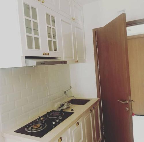 Il comprend une cuisine équipée d'une cuisinière et de placards blancs. dans l'établissement Apartement Podomoro golf view exit toll cimanggis, à Bogor