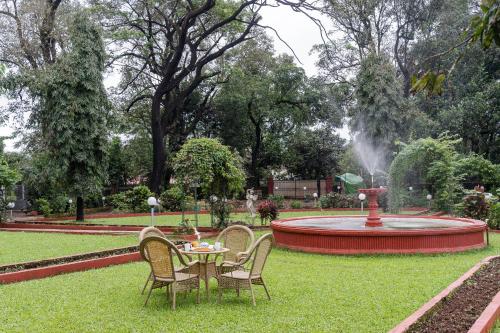 a table and chairs in front of a fountain at SaffronStays Mosaic - 4 Bedroom Heritage Villa With Large Lawns In Khandala in Khandala
