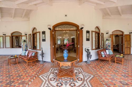 a living room with chairs and a table in a room at SaffronStays Mosaic - 4 Bedroom Heritage Villa With Large Lawns In Khandala in Khandala