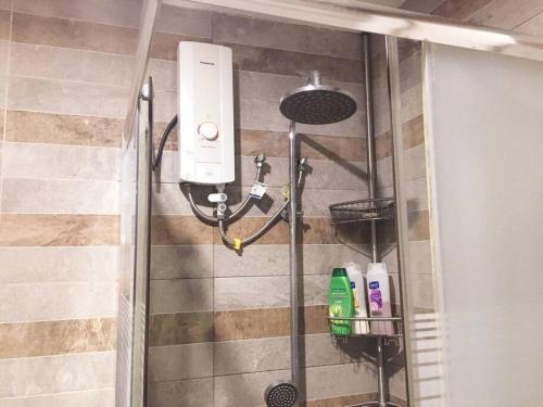 a shower with a shower head and two bottles of soap at Bagasbas House in Daet