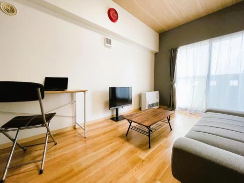 a room with a bed and a table and a tv at 新規OPEN札幌駅徒歩圏内10-1【サービスアパートメントSAPPORO札幌ステーション】 in Sapporo