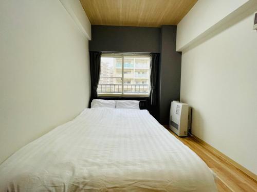 a bedroom with a large white bed and a window at 新規OPEN札幌駅徒歩圏内10-1【サービスアパートメントSAPPORO札幌ステーション】 in Sapporo