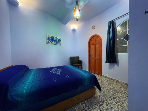 a bedroom with a blue bed and a chair at Dar Fatima in Chefchaouene