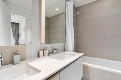 Baño blanco con 2 lavabos y espejo en Supreme Luxury 2BR Apartment en Dubái