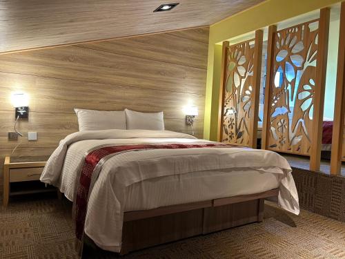 a bedroom with a large bed with a wooden wall at 埔里夏都華蔓山林日式會館 Puli Huaman Villa in Puli