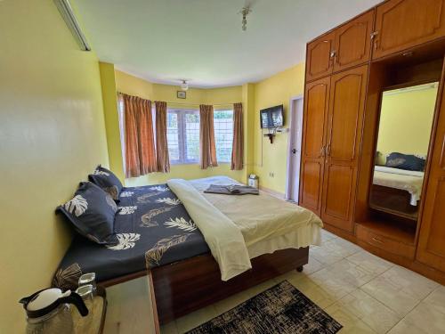 1 dormitorio con 1 cama en una habitación con paredes amarillas en Priyadeep BnB en Ooty