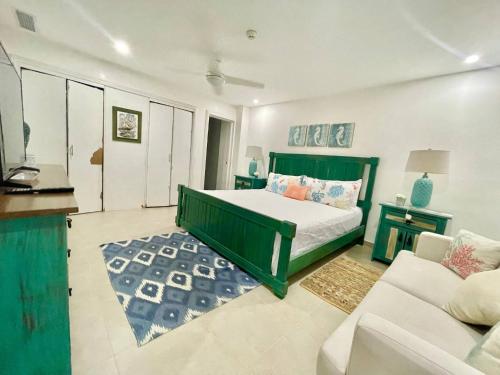 um quarto com uma cama verde e um sofá em 2 Bedroom At The Marbella Towers Beachfront num1705 em Juan Pedro