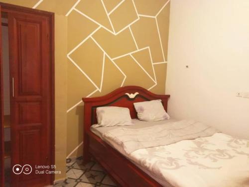 una piccola camera da letto con un letto con lenzuola bianche di Ramakyri rom a Douala