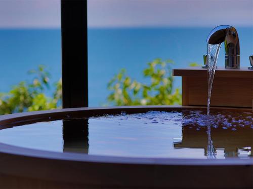 a hot tub with water coming out of it at 海のほてる　いさば in Numazu