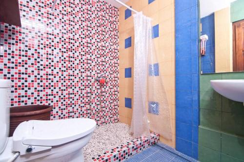y baño con ducha, aseo y lavamanos. en Large House with Swimming Pool-Griya Alcheringa, en Bedoyo