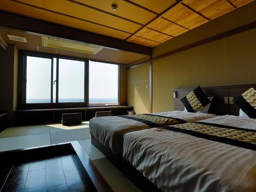 a bedroom with two beds and a large window at 海のほてる　いさば in Numazu