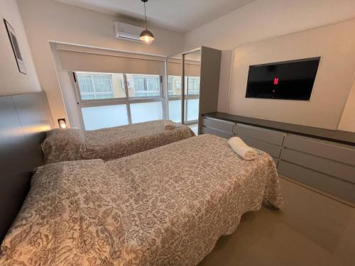 a bedroom with two beds and a flat screen tv at Urban Luxury Studio Living in San Telmo num4649 in Buenos Aires
