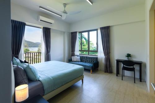 a bedroom with a bed and a desk and windows at By The Sea Beach Front Apartment in Batu Ferringhi