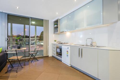 a kitchen with white cabinets and a dining room with a table at Strathfield sweet 2Br near Train StationShopping in Sydney