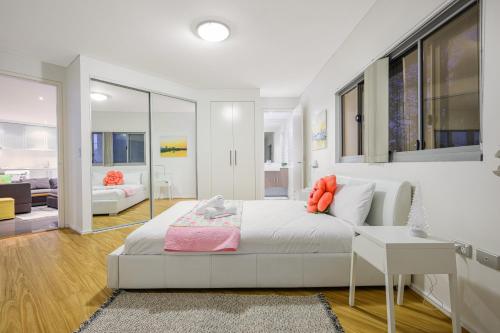 a white bedroom with a bed and a living room at Strathfield sweet 2Br near Train StationShopping in Sydney