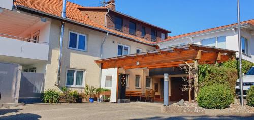 een huis met een houten pergola ervoor bij FeWo Weishaupt in Tettnang