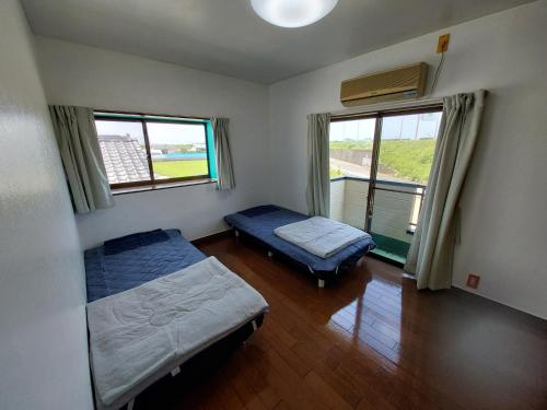UMICHIKA HOUSE في ميازاكي: غرفة نوم صغيرة بسريرين ونافذة