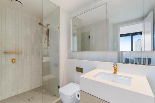 a white bathroom with a sink and a shower at Collins House Apartments by CLLIX in Melbourne