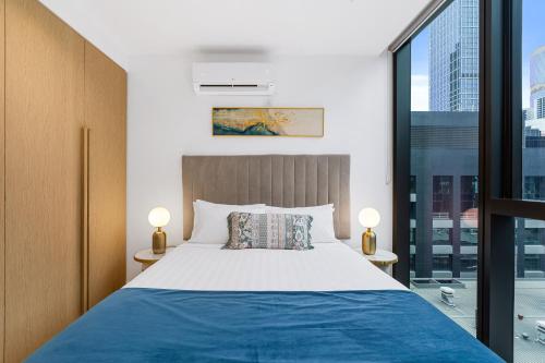 a bedroom with a bed and a large window at Collins House Apartments by CLLIX in Melbourne