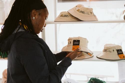 a woman is looking at hats on a shelf at Matatane Camp - Babanango Game Reserve in Nkwalini