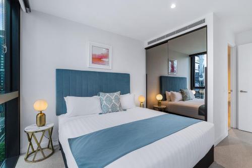 a bedroom with a large bed and a mirror at Collins House Apartments by CLLIX in Melbourne