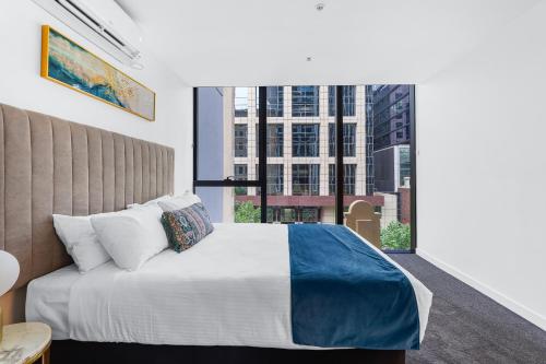 a bedroom with a bed and a large window at Collins House Apartments by CLLIX in Melbourne