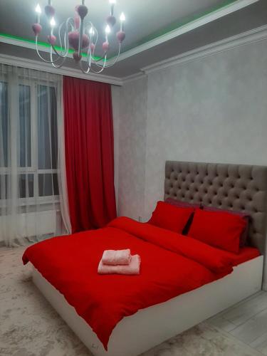 - une chambre avec un lit rouge et un lustre dans l'établissement Красивая квартира в центре городе Шымкент. ЖК Аль-Фараби, à Chimkent