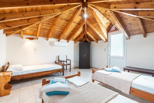 una camera con tre letti e un soffitto in legno di White Pearl a Lakhania