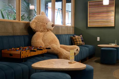 平塚的住宿－miss morgan hotel，坐在一张长沙发上,摆着一张带棋盘的大泰迪熊