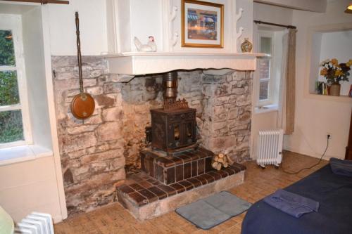 sala de estar con chimenea de piedra y fogones en cottage a la ferme, en Lengronne