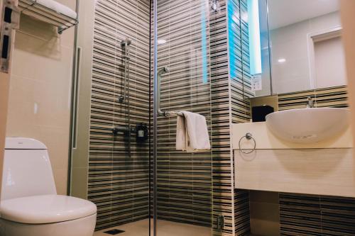 a bathroom with a shower and a toilet and a sink at Trinidad Suites Johor, Trademark Collection by Wyndham in Nusajaya