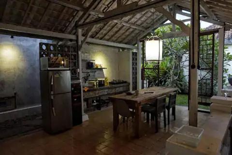 uma cozinha com uma mesa e cadeiras e um frigorífico em East room at Semadi Living em Darmasaba