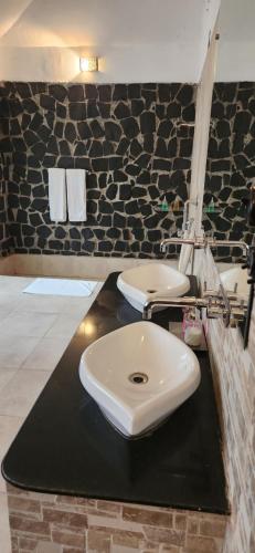 baño con lavabo blanco en una encimera negra en Bandhavgarh Meadows, en Tāla