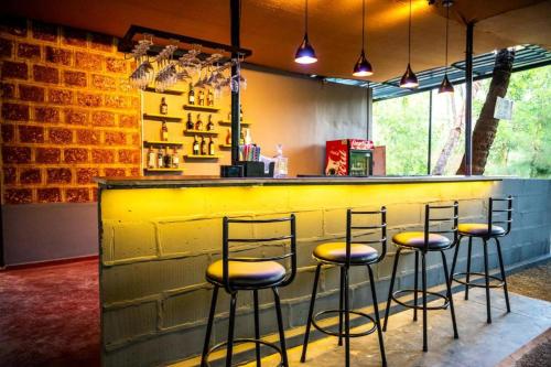 a bar with four stools in front of a yellow counter at Vintage Beach Resort in Agonda