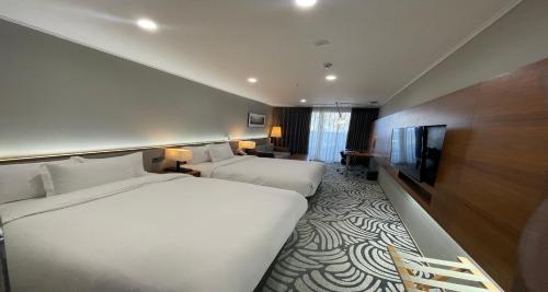 a hotel room with two beds and a flat screen tv at Best Western Plus GyeongJu in Gyeongju