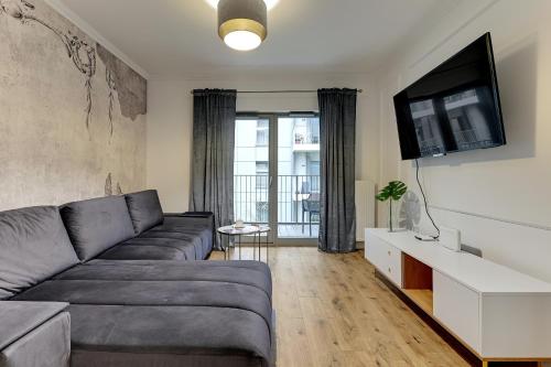 a living room with a couch and a flat screen tv at GRANO APARTMENTS Gdańsk Old Town SPA & Wellness - GRANO APARTMENTS Gdańsk Residence SPA & Wellness in Gdańsk
