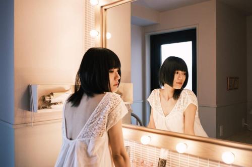 Eine Frau, die ihr Spiegelbild in einem Badezimmerspiegel sieht. in der Unterkunft miss morgan hotel in Hiratsuka