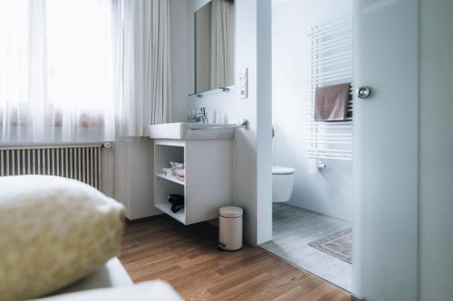 a white bathroom with a sink and a toilet at Gästehaus Lässer in Mellau