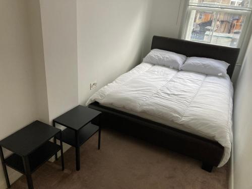 a bed in a room with two tables and a window at Two double bedroom flat in Soho in London