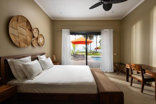 a bedroom with a bed and a patio with an umbrella at Alma Villas in Nosy Be
