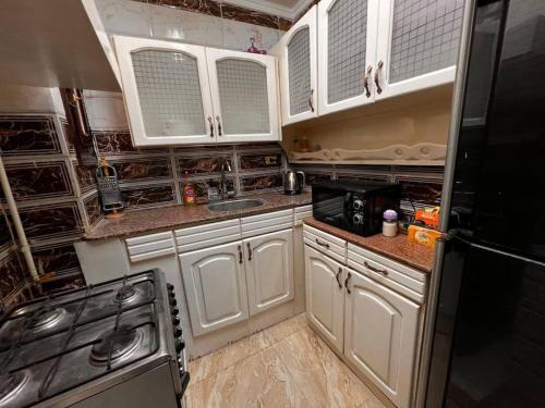 La cuisine est équipée de placards blancs et d'un réfrigérateur noir. dans l'établissement Luxe apartment Nile View Downtown, à Assouan