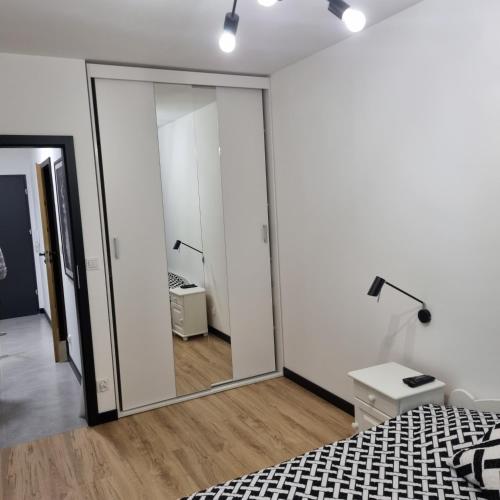 Dormitorio con espejo, cama y lámpara en Komfortowy apartament en Toruń