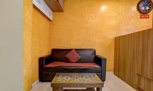 a living room with a leather couch and a table at FabExpress Prakash Inn in Mumbai