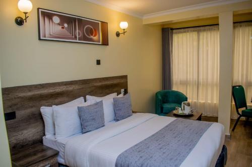 una habitación de hotel con una cama grande y una silla en The Kolel Hotel and Suites en Eldoret