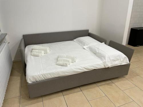 uma cama grande com lençóis brancos e almofadas em B&B Mandorli 29 em San Colombano al Lambro