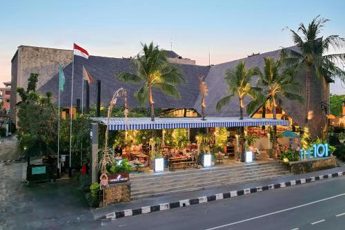 a restaurant on the side of a building with palm trees at THE 1O1 Bali Oasis Sanur in Sanur